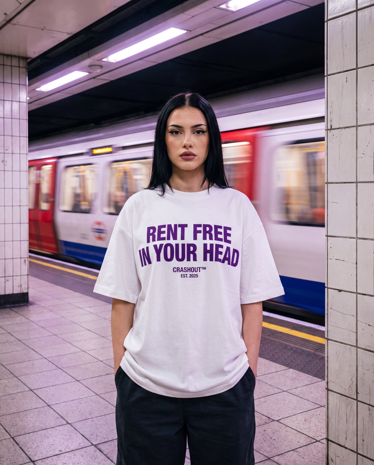 Model on a subway platform as a train blurs past, wearing a Rent Free tee